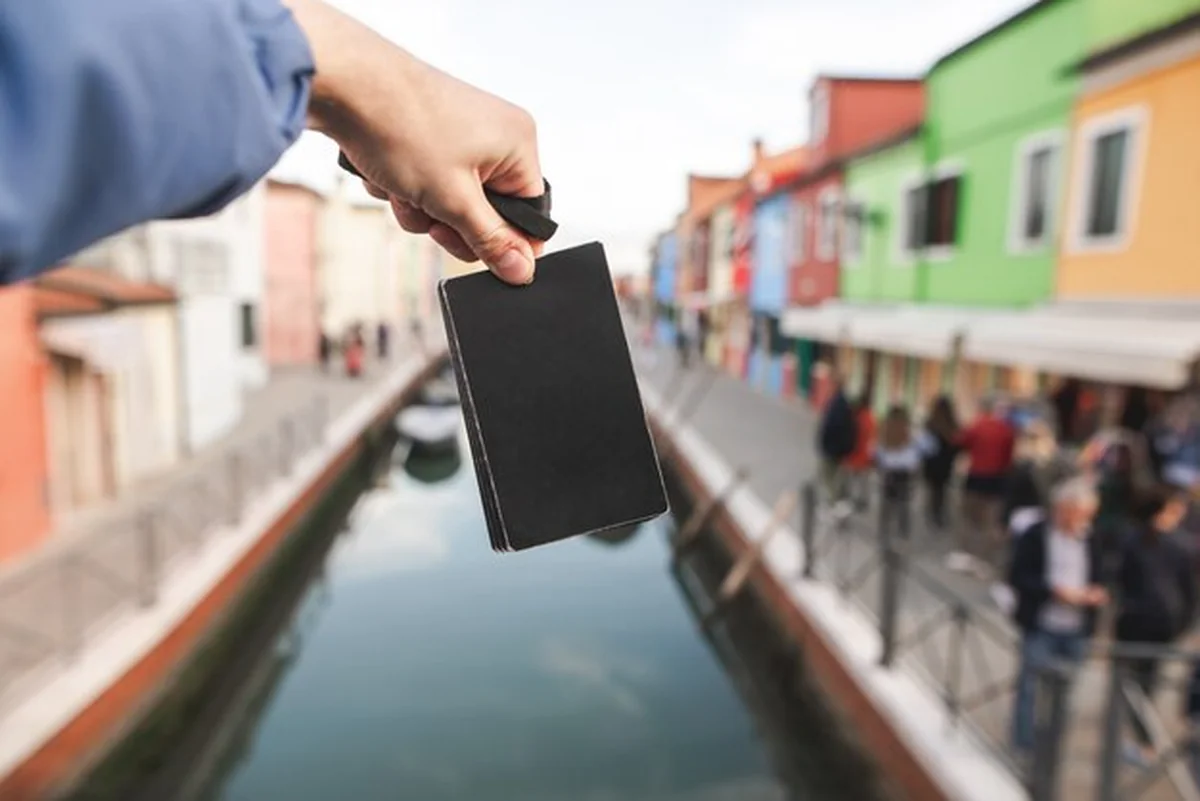 Młody człowiek trzymający pustą kartę na tle kolorowych domów na wyspie Burano w Wenecji