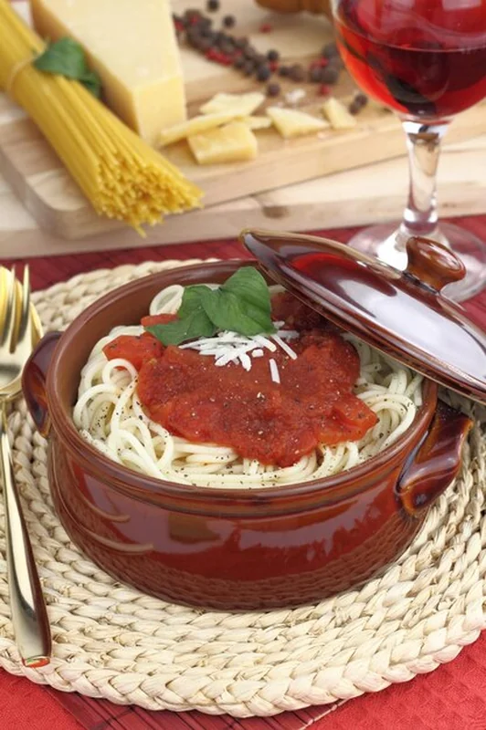 Makaron spaghetti z serem w sosie pomidorowym i bazylią w glinianym garnku