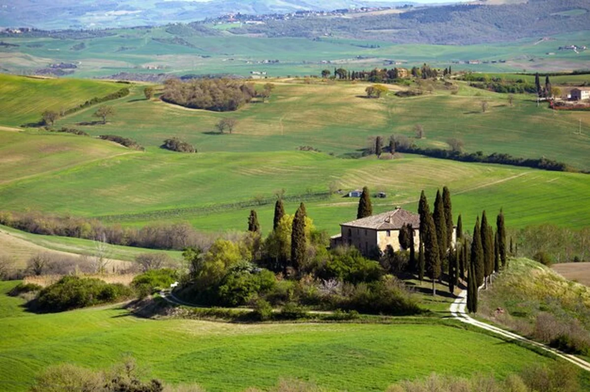 Typowy toskański krajobraz - willa na wzgórzu, zielone pola, słoneczny dzień, prowincja Siena