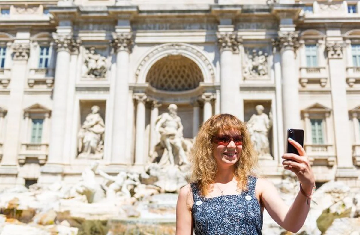 Młoda kobieta turystka robi selfie przy Fontannie di Trevi w Rzymie