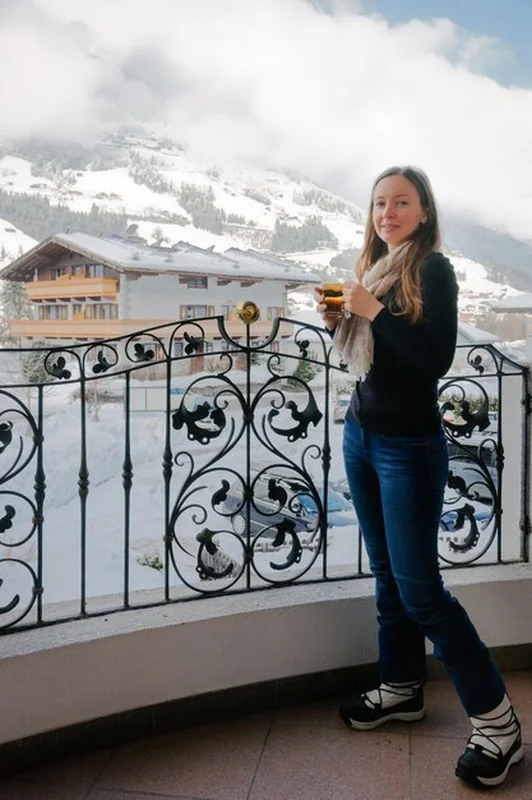Szczęśliwa kobieta na balkonie picia herbaty w zimowej dolinie Alp