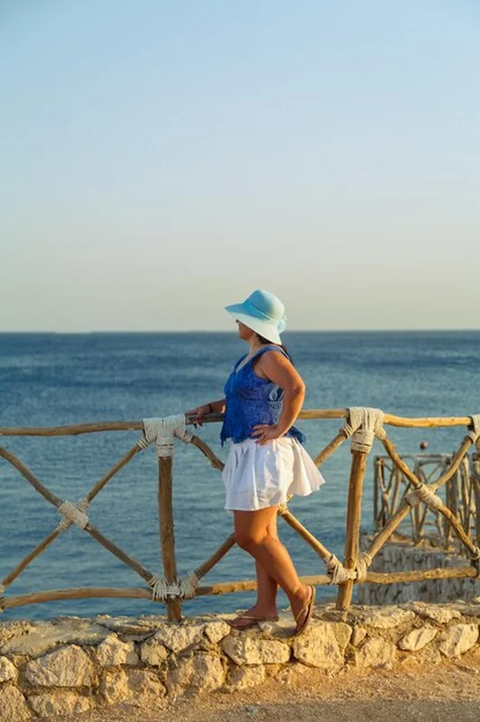 Młoda brunetka nad morzem w białej spódnicy i kapeluszu