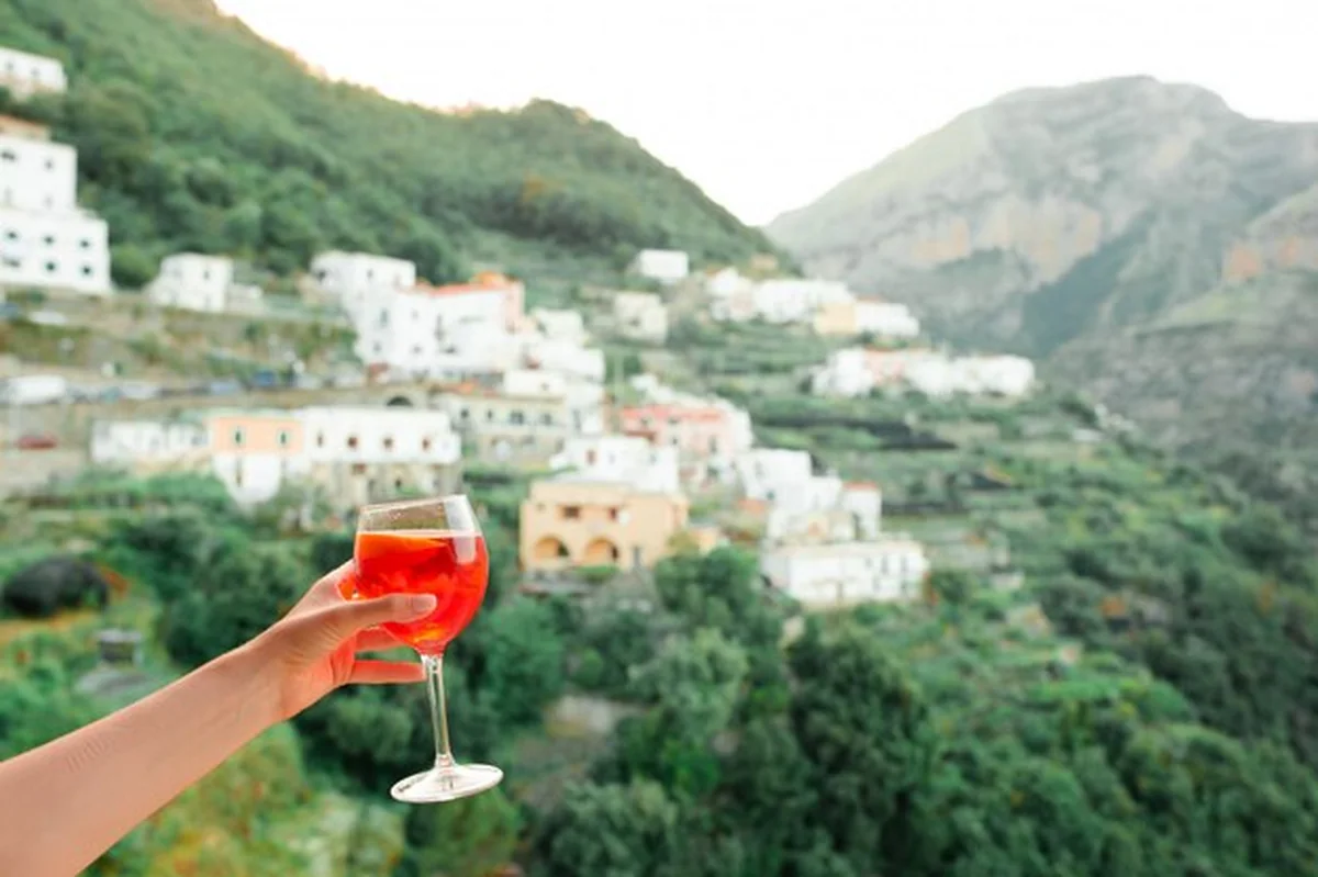 Ręka trzymająca szkło z Aperol Spritz na włoskiej wiosce na Amalfi